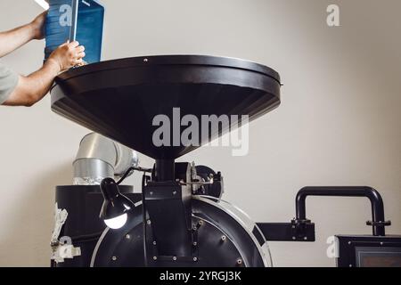 Close-up of Worker Pouring Coffee Beans Into Roaster During Roasting Process in Roasting Factory Stock Photo