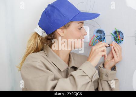 female electrician fixing electric cables in socket Stock Photo