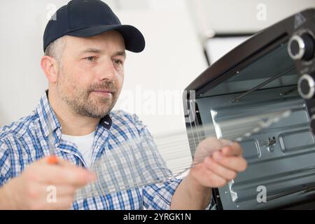 serviceman in overall working on fridge Stock Photo