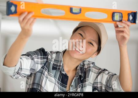 smiling female worker using a spirit level Stock Photo