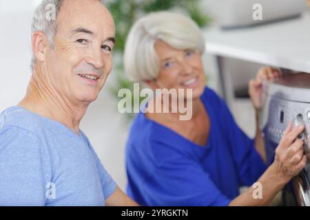 portrait of happy senior couple doing laundry Stock Photo