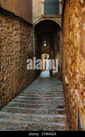 Stone steps ascend through a narrow, arched passageway in girona's old town, showcasing the city's medieval architecture and timeless charm Stock Photo