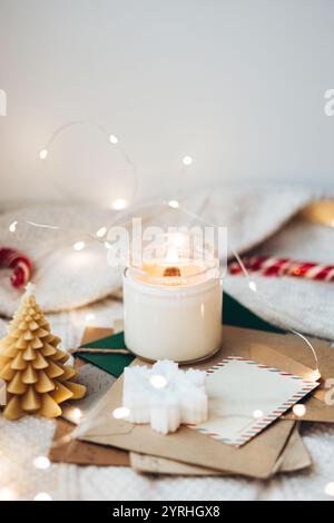 Warm and inviting Christmas scene featuring a lit candle, a small tree, and envelopes with holiday decorations Soft lights and cozy accents create a f Stock Photo