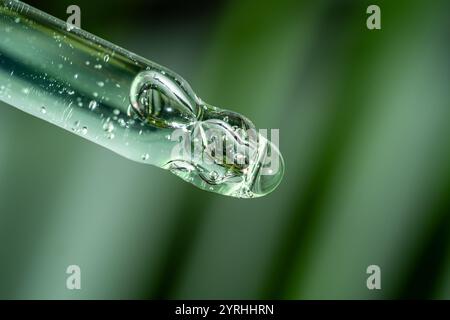 A close-up of a serum-filled cosmetic pipette against soft, blurred green leaves Ideal for illustrating skincare, beauty products, and nature-inspired Stock Photo