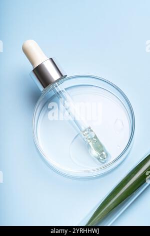 A clear dropper with liquid in a glass dish set against a soft blue backdrop. Ideal for illustrating concepts of skincare, beauty, or scientific resea Stock Photo