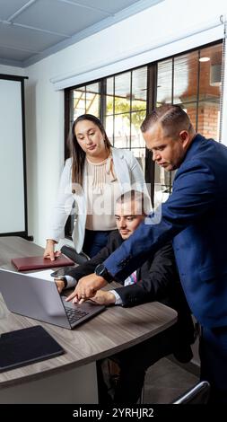 A group of Latino lawyers discussing legal strategies during a business meeting They are reviewing documents on a laptop around a modern conference ta Stock Photo