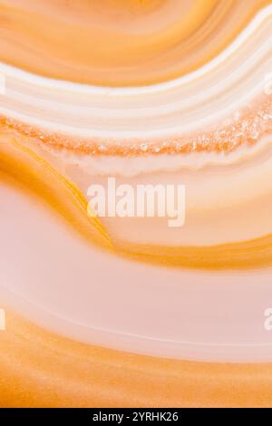 Close-up of a Brazilian agate slice featuring warm, earthy swirls and patterns The agate is backlit, highlighting its natural translucency and layered Stock Photo