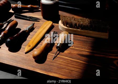 A set of traditional leather crafting tools neatly arranged on a wooden table The image captures the rustic charm of artisanal leather work, highlight Stock Photo