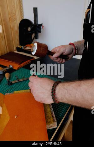A craftsman works meticulously on leather goods in a workshop, using specialized tools The image captures the essence of traditional leather crafting Stock Photo