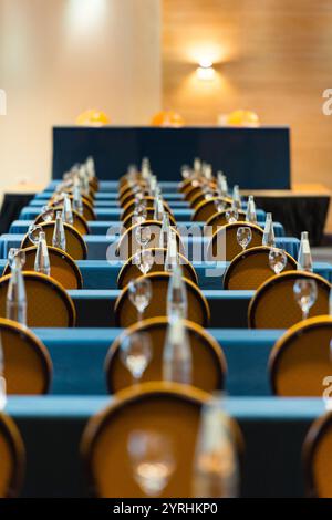 Rows of chairs with elegant table settings in a modern conference room Bottles and glasses are neatly arranged, creating a professional and formal atm Stock Photo