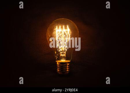 Vintage incandescent light bulb glows on black background. Think different, concept. Creative idea. Electricity Stock Photo
