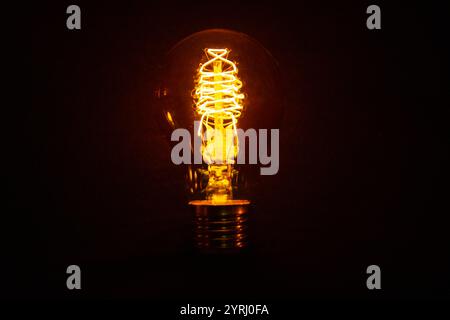 Vintage incandescent light bulb glows on black background. Think different, concept. Creative idea. Electricity Stock Photo