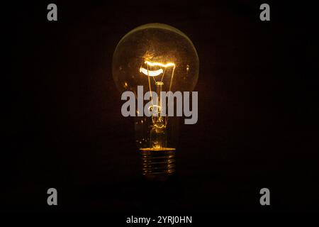 Vintage incandescent light bulb glows on black background. Think different, concept. Creative idea. Electricity Stock Photo