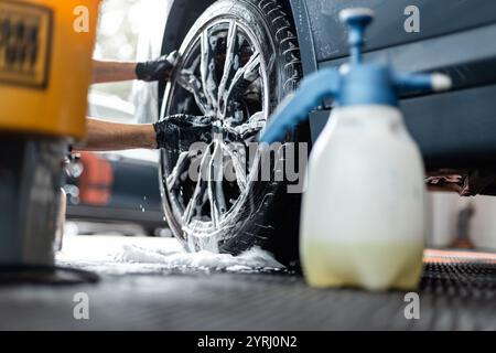 professional man washes car wheels with his hands in a detailing studio. Car care and washing in a garage Stock Photo