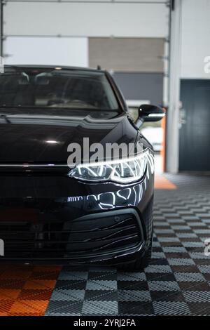 Black car with optics headlights is in the garage. Car wash. Detailing. Repair Stock Photo