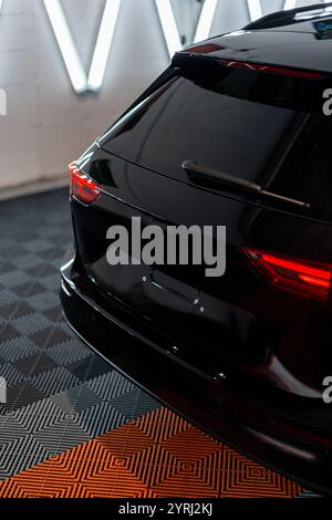 Black car with tail light in garage. Car wash and detailing. Repair Stock Photo