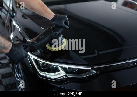 Professional man polishing black car. Car care and polishing. Scratch removal. Detailing Stock Photo