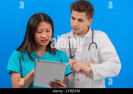 Medical team reviewing patient information on a tablet in a clinical setting Stock Photo
