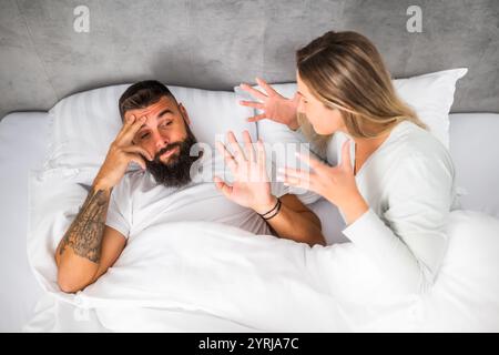 Couple is lying in bed and arguing. The woman is angry with the man. Stock Photo