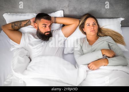 Couple is lying in bed. They are angry and not talking to each other. Stock Photo