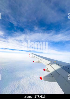 View of british airways airplane wing soaring above the clouds with a vibrant blue sky in the background Stock Photo