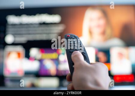 Person's hand changing tv programs by using smart tv remote control. Close up view. Stock Photo