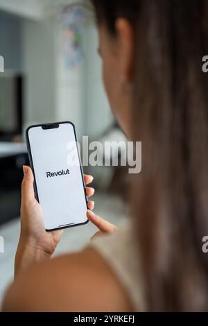 Prague, Czech republic - May 2, 2024: Woman holding iPhone with logo of application Revolute on the screen, using mobile application for business home Stock Photo