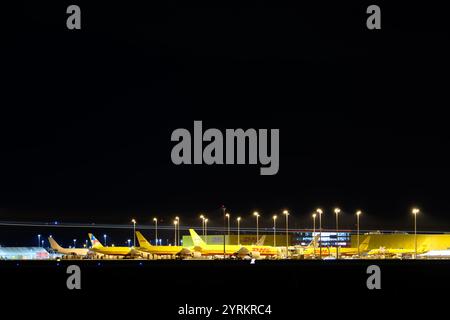 PRODUCTION - 26 November 2024, Saxony, Leipzig: DHL aircraft stand at the DHL freight center at Leipzig/Halle Airport in the late evening. With the DHL hub of Post subsidiary DHL, the airport is one of the world's most important centers for air freight. Photo: Hendrik Schmidt/dpa Stock Photo