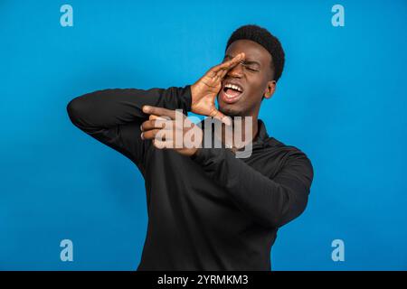 Young adult making an announcement, shouting and pointing on a blue background Stock Photo