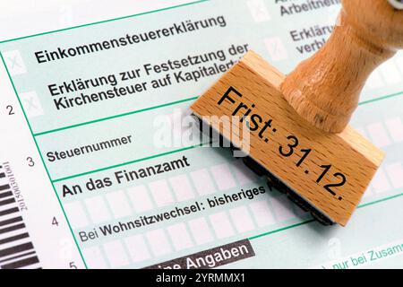 Frist für die Abgabe der Steuererklärung an das Finanzamt Ein Holzstempel mit dem Aufdruck Frist: 31.12. liegt auf einem Formular zur Einkommensteuere Stock Photo