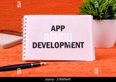 The concept of technology and business development. The APP DEVELOPMENT concept phrase It is written on a clean notebook on an orange background. Stock Photo
