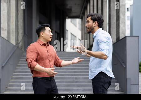 An intense exchange between two colleagues on office stairs captures a moment of workplace conflict. The image reflects emotions such as anger and stress, highlighting professional disagreements. Stock Photo