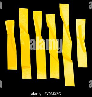 Top view set of wrinkled or crumpled yellow adhesive vinyl tape or cloth tape in stripes shape is isolated on black background with clipping path. Stock Photo