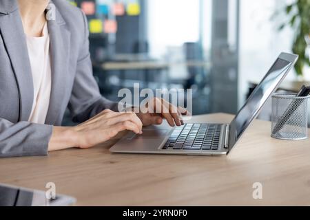 Mature woman businesswoman typing on a laptop in a modern office setting. Her focused expression highlights productivity and professionalism, embodying concepts of business and technology. Stock Photo