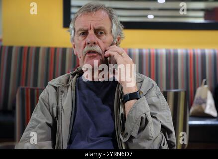 Elderly Man Talking on iPhone at Heathrow Airport England Stock Photo