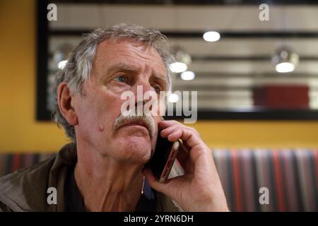 Elderly Man Talking on iPhone at Heathrow Airport England Stock Photo