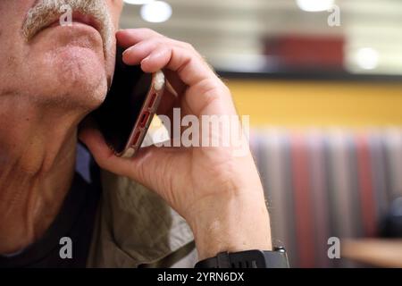 Elderly Man Talking on iPhone at Heathrow Airport England Stock Photo