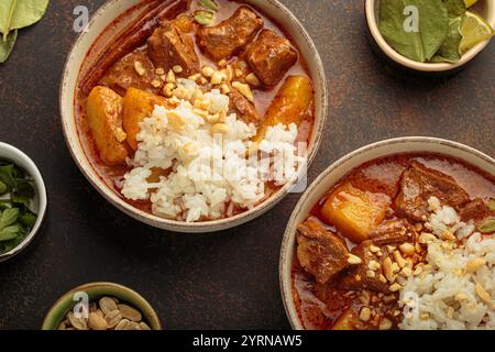 Two bowls of massaman curry with beef, potatoes, rice, and peanuts served in bowls top view, traditional Thai cuisine Stock Photo