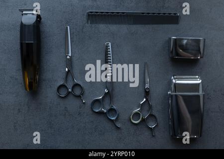 Barbershop tools set: scissors, shaving trimmer, hair clipper and comb lie on gray background, top view. Haircut and hair care, creative Stock Photo