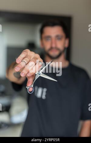 Male hairdresser holding scissors in hand, close-up. Barbershop Stock Photo