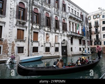 Tourists on a Gondola ride along a water canal on the streets of Venice, Italy Stock Photo