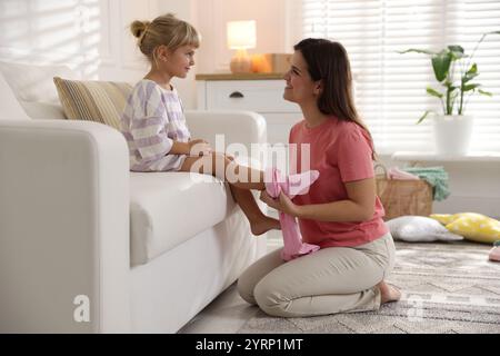 Mother helping her daughter to put tights on at home Stock Photo