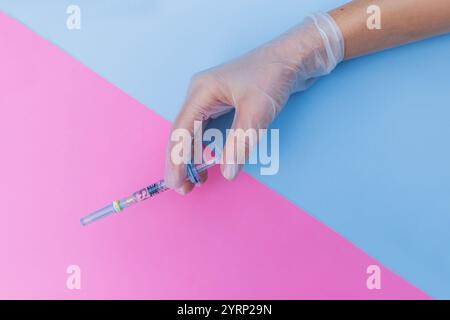 Female hand in glove holds botox filler injection on blue pink background. Beauty and injection, concept. Creative idea medicine and beauty Stock Photo