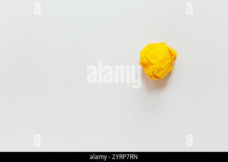 crumpled yellow piece of paper on a white sheet of paper. Creative idea. Stock Photo