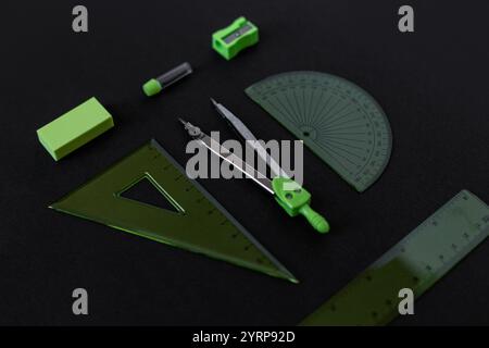 set of green geometry tools: rulers, compasses, eraser and sharpener lie on a dark background. Mathematics and lesson at school Stock Photo