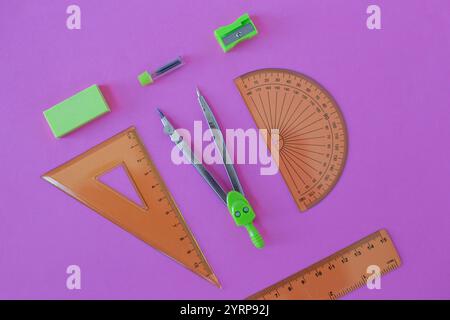 set of green geometry tools: rulers, compasses, eraser and sharpener lie on a pink background. Mathematics and lesson at school Stock Photo