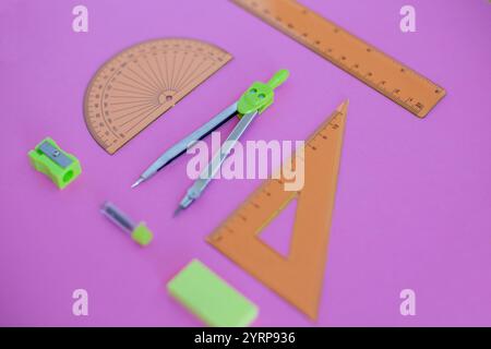 set of green geometry tools: rulers, compasses, eraser and sharpener lie on a pink background. Mathematics and lesson at school Stock Photo