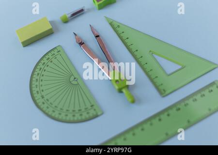 set of green geometry tools: rulers, compasses, eraser and sharpener lie on a blue background. Stock Photo