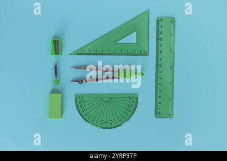 set of green geometry tools: rulers, compasses, eraser and sharpener lie on a blue background. Stock Photo