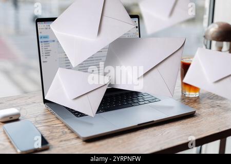 Laptop with open webmail service site and flying mail in office stands on table on a urban background. Mail and work, concept. Incoming mail, creative Stock Photo